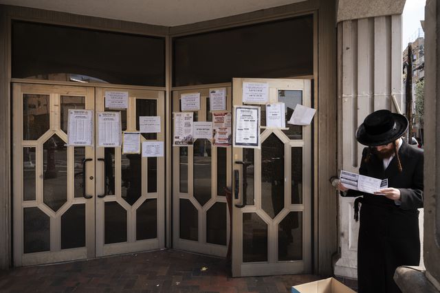 Man stops to read an announcement at Congregation Divrei Yoel in the Williamsburg neighborhood of Brooklyn, in New York. The synagogue is closed to gatherings due to the coronavirus.